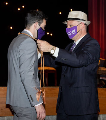Wayd Davis receives his honors cords from Dr. Brad Johnson.