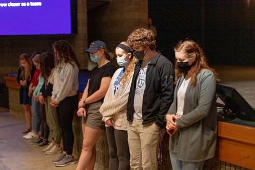 Students standing together being prayed for.