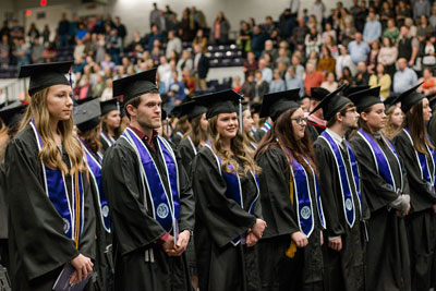 graduates stand at attention during commencement ceremony