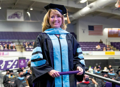 female doctor of education graduate smiles as she receives diploma