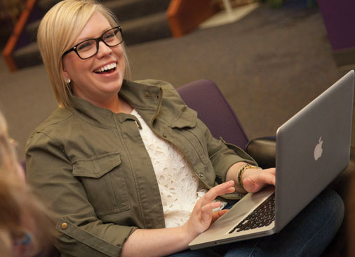 female student types on laptop and smiles