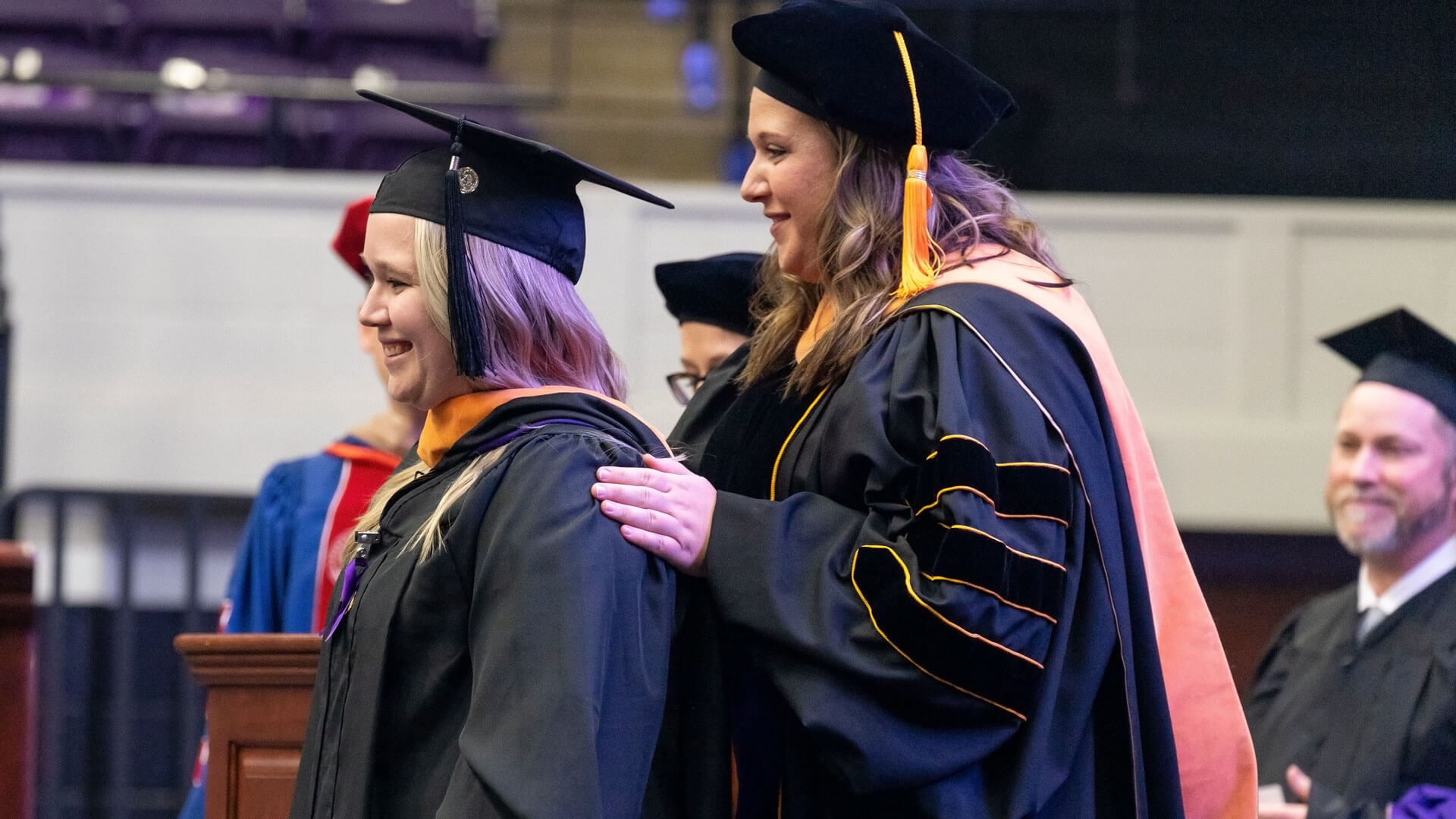 nursing graduate receives master's hood from professor during commencement ceremony