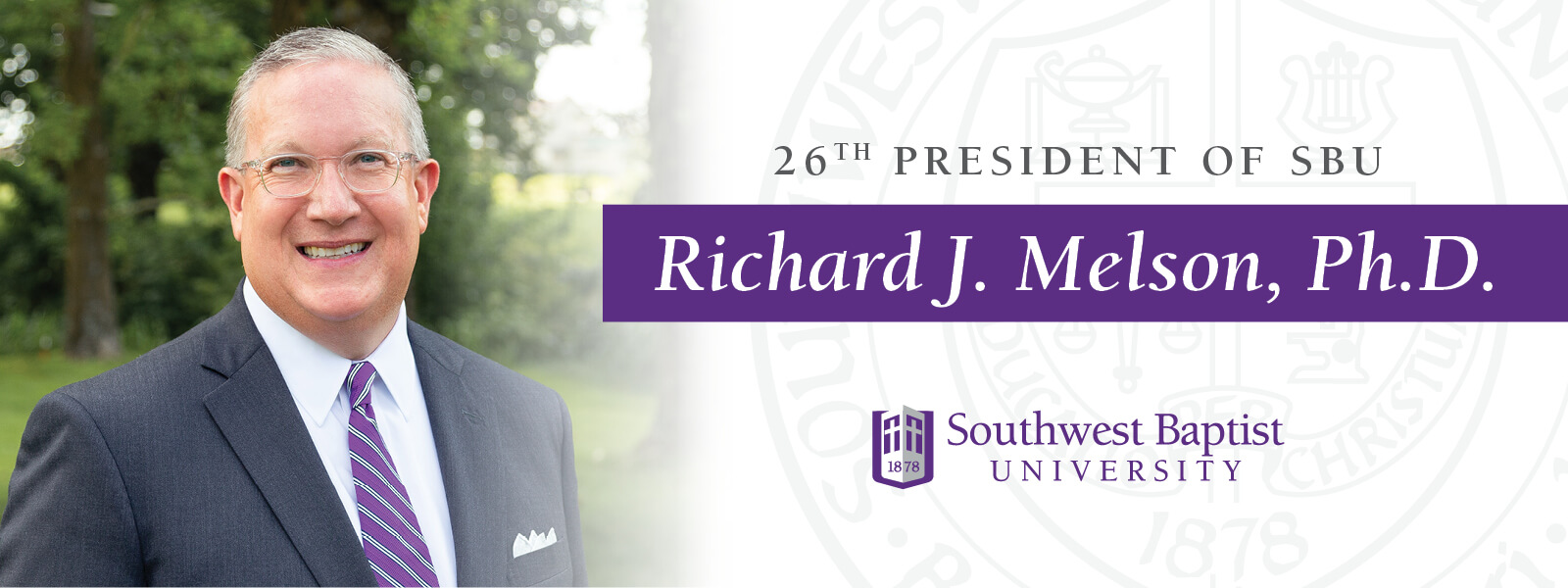 Dr. Melson standing in front of globe water sculpture on S-B-U campus