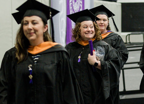 nursing graduates smile as they leave commencement stage