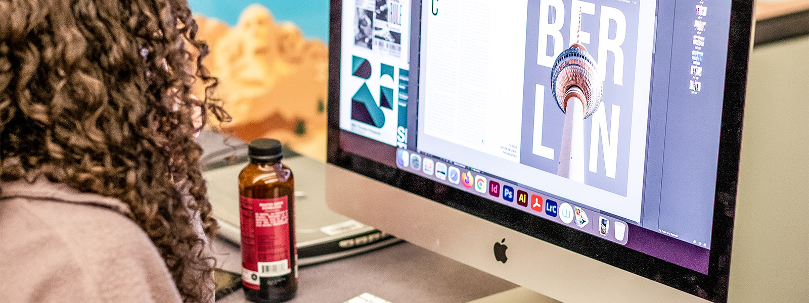 students working on graphic design projects on large Mac computers