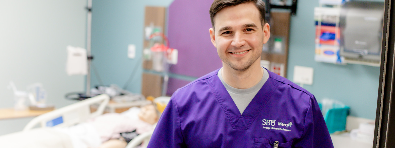 nursing student smiling with simulation lab in background