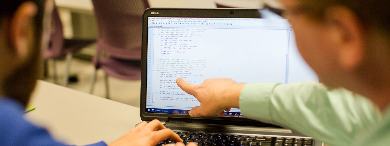 view of code on computer screen as professor helps student