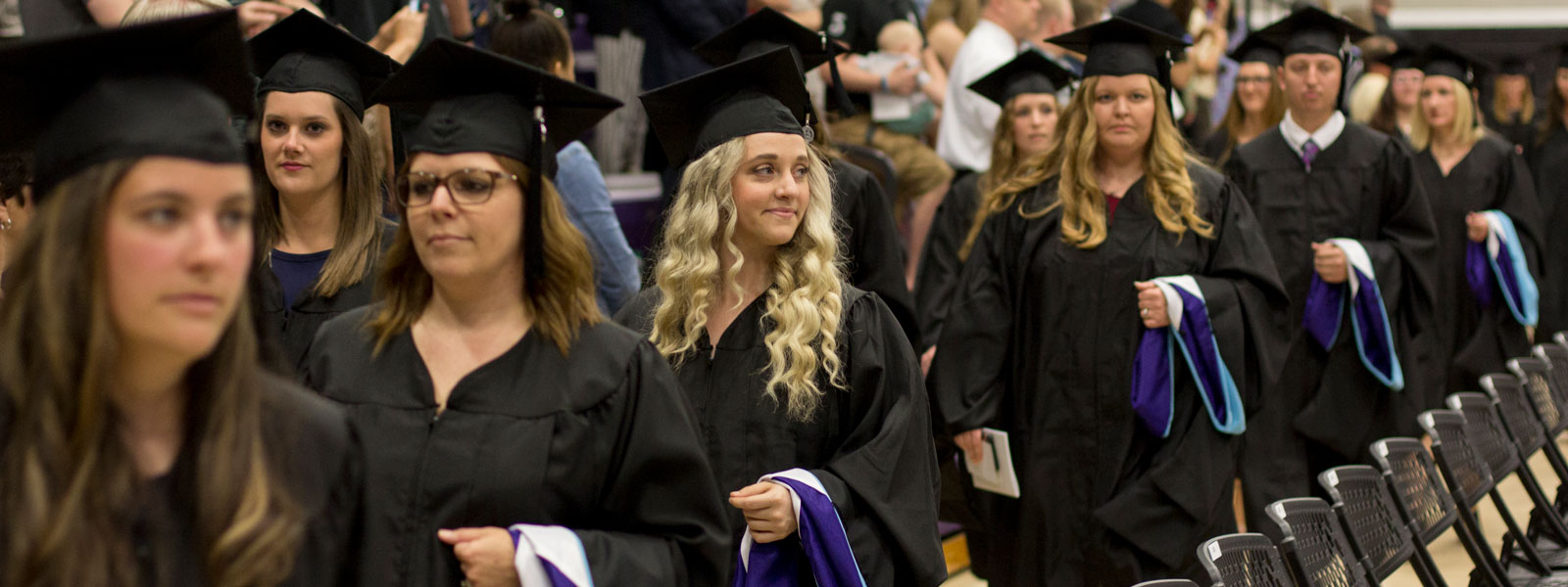 graduates walk in commencement processional holding master's hoods