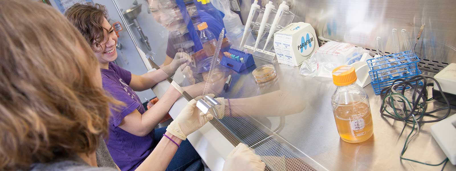 student smiles while working in microbiology lab