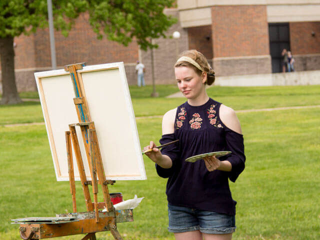 Female art student working on painting outside
