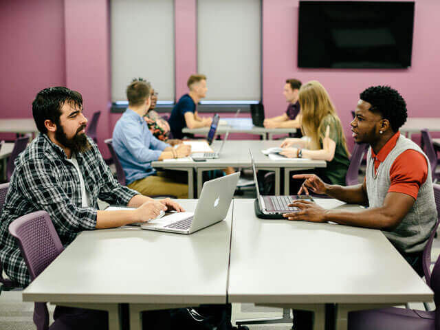 students working on laptops inside classroom