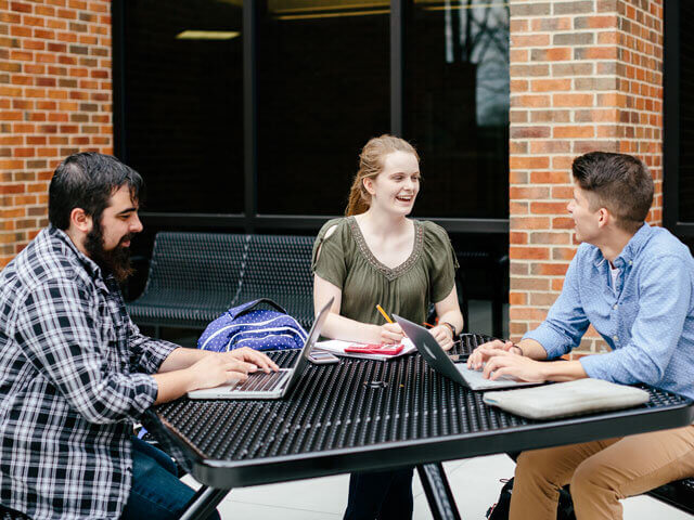 Students working on group projects at outside table