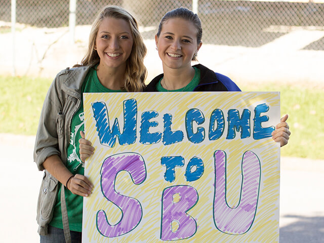 two girls holding welcome to S-B-U sign